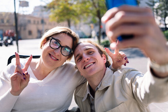happy couple of a man and woman using wheelchair taking a selfie photo with mobile phone, concept of friendship and technology of communication