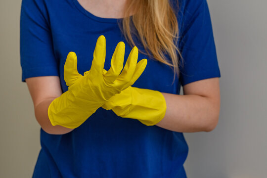 Sprzątaczka zakłada gumowe żółte rękawice do sprzątania 