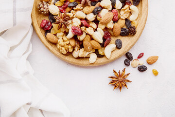 Aesthetic wooden bowl with assorted nuts, raisins and cranberries from above. Walnuts, almonds, hazelnuts and cashews. Healthy snacks and desserts