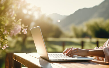 Digital nomad woman working at a table with a computer in the background views of a mountain and a valley. Work online in travel concept