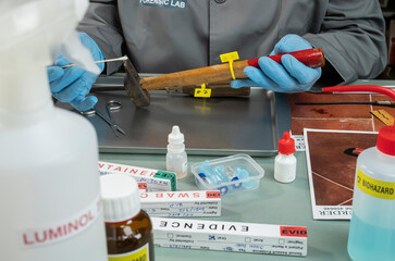 Police scientist extracts DNA sample from a pair of hammer in a crime lab, concept image