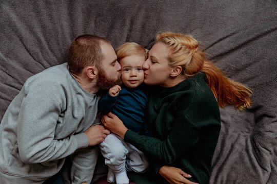Family with baby in bed, kissing and hugging kid