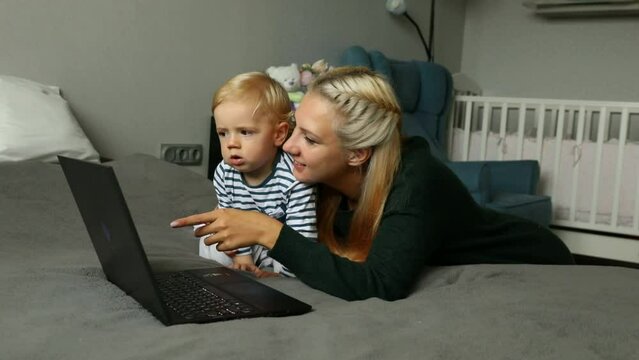 Mom with kid with computer at home on the bed