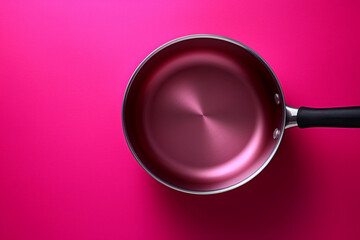 stainless steel frying pan on a pink background