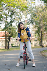 asian woman biking bicycle with her cat in backpack at park