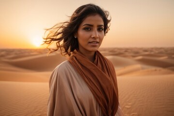 Fototapeta premium Arabic woman walking on sand dunes at sunset