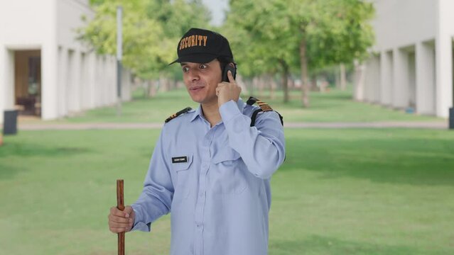 Happy Indian security guard talking on phone