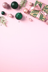 Vertical Christmas banner design, poster template. Green and pink Xmas balls ornaments, gift box, fir tree branches, confetti on light pink background. Chic Style.