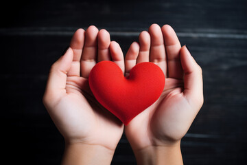 Hands cradling a red heart symbolizing love and care.
