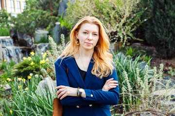 female woman with long orange colored hair with cross arms on chest in garden. architect landscape...