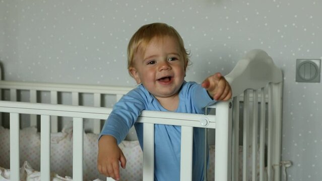 Baby in blue pajamas in baby cradle smiling