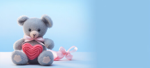 Knitted gray bunny with a crocheted pink heart on a blue background