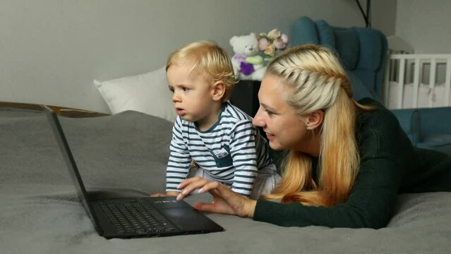 Mom with kid with computer at home on the bed