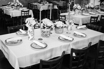 Black and white of a beautifully set dinner wedding table in front of a large window