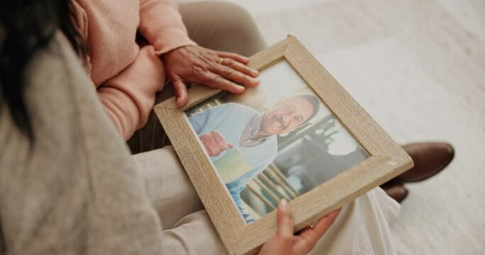 Sad, hug and a daughter with a mother and a photo for grief, loss or a memory. Comfort, love and a girl with care for senior mom looking at a picture frame to remember together on a home sofa