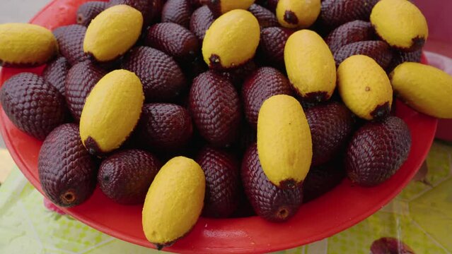 Closeup shot of the Buriti Fruits a plastic red bowl with blur background