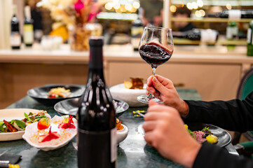 Young man hand holding a glass with red wine in a restaurant
