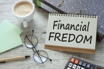 Financial Freedom a cup of coffee. glasses. two office folder gray notepad. text on the page