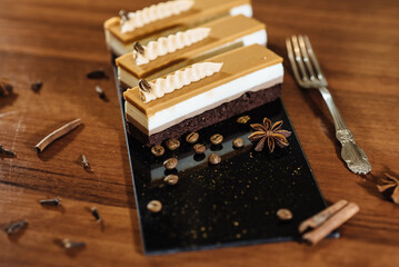 Three chocolate cakes on a black background. Mousse cake. Opera cake at the a La carte desserts , cakes on a black background. Selective focus. Cake with salted caramel