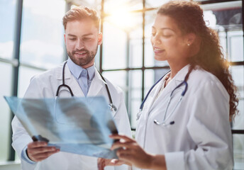 Young serious competent male doctor looking at X-ray at doctor's office