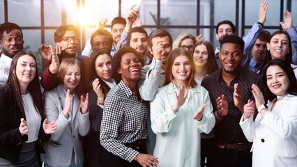 Group of young businesswomen smiling happy and clapping. Standing and looking to the camera at the...