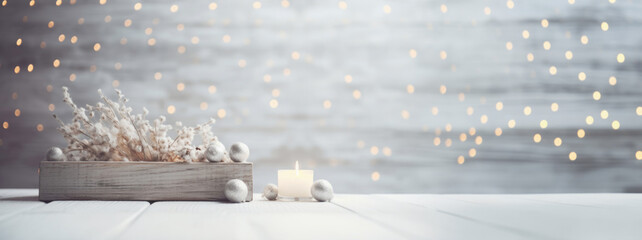 Christmas decorations in a wooden box and a burning candle on a white wooden table with bokeh in...