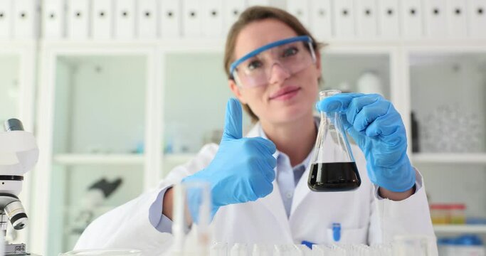 Chemical industrial laboratory scientist holding black liquid crude oil in flask and thumbs up. Quality and approved examination of petroleum products