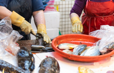 Merchants fillet fish on a white chopping board in a traditional market, chefs fillet fish at a table.	
