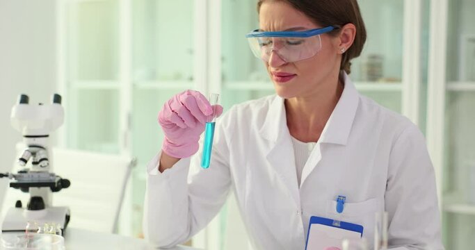 Scientist holds test tube and smells stinking and disgusting unbearable smell. Biologist holding his breath and toxic smell