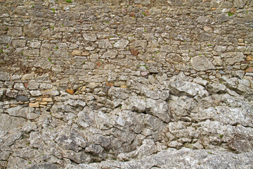 Medieval wall, consisting of rough-hewn stones, built on rock