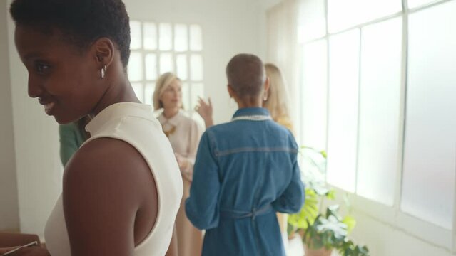 Cinematic footage of a multiethnic group of women managing new projects in a start up business. Female colleagues working as a team in the office wearing elegant colored diverse outfits