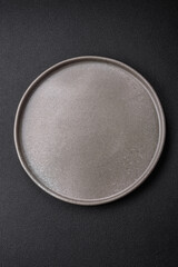 Empty round ceramic plate on a dark textured background