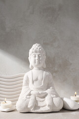 Buddha statue, candles and stones on beige background