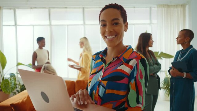 Cinematic footage of a multiethnic group of women managing new projects in a start up business. Female colleagues working as a team in the office wearing elegant colored diverse outfits