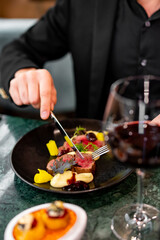 man hands eats meat with red wine in a restaurant