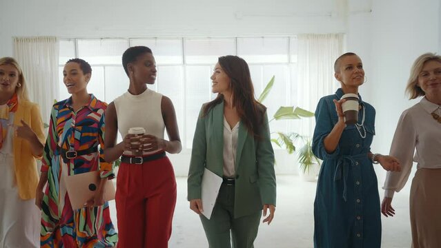 Cinematic footage of a multiethnic group of women managing new projects in a start up business. Female colleagues working as a team in the office wearing elegant colored diverse outfits