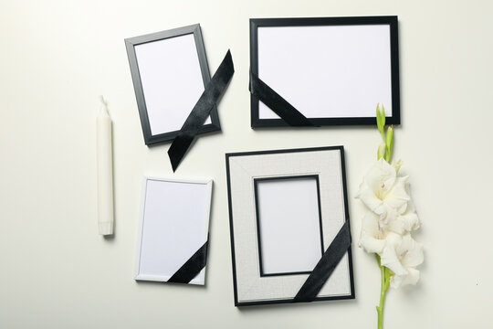 Photo frames with black ribbons, flower and candle on white background, top view