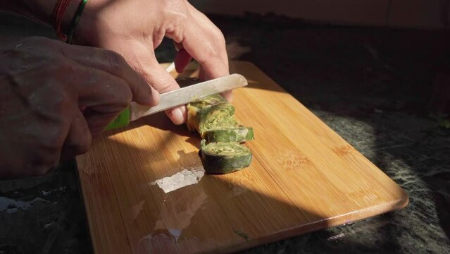 indian woman making slices of steamed vegetable roll alu vadi. aluvadi, ptrode, patri popular maharashtrian and Gujrati snack.