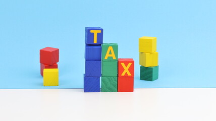 Obraz premium The word Tax written with wooden blocks and colored sheets, on the table, copy space.