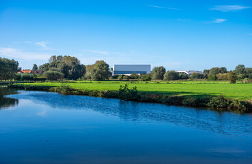 Fototapeta na wymiar Industrial buidling reflecting in the water of the river Dender, Ninove, Flemish Region, Belgium