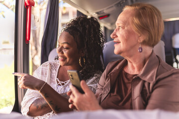 Young man showing something through the window to a senior woman during a bus ride.
