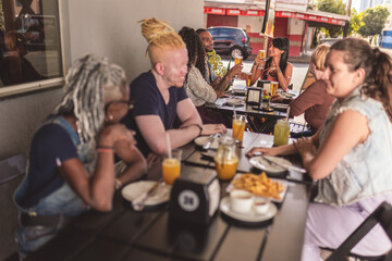 Pessoas diversas, sorrindo, se divertindo, durante happy hour em bar ao ar livre.