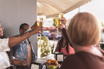 Diverse group of smiling friends toasting at a table in a bar, during happy hour.
