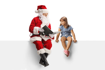 Santa claus sitting on a blank panel and reading a book to a little girl
