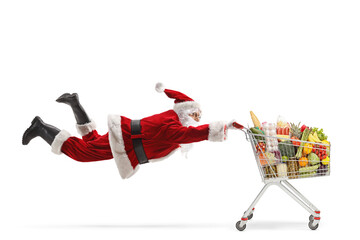 Santa claus flaying and holding a shopping cart with food