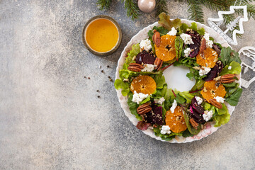Christmas appetizer. Christmas wreath salad with beetroot, tangerines, feta cheese and pecans on the festive table. View from above. Copy space.