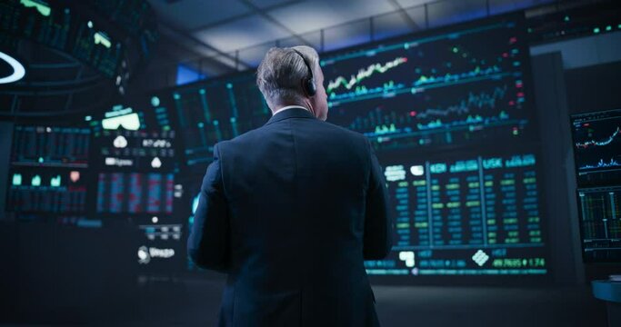 Footage from the Back of a Middle Aged Man Working on the Floor in a Modern Stock Exchange Firm. Specialist Monitoring Companies and Funds, Securities, Derivatives, Investment Products and Bonds