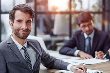 young man posing for the camera while sitting at the table in the office