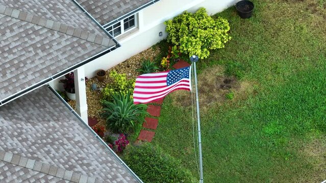 American national flag waving in front yard of Florida private house. Aerial view of USA stars and stripes spangled banner as symbol of democracy