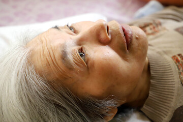 介護ベッドで横になって休む高齢のシニア女性